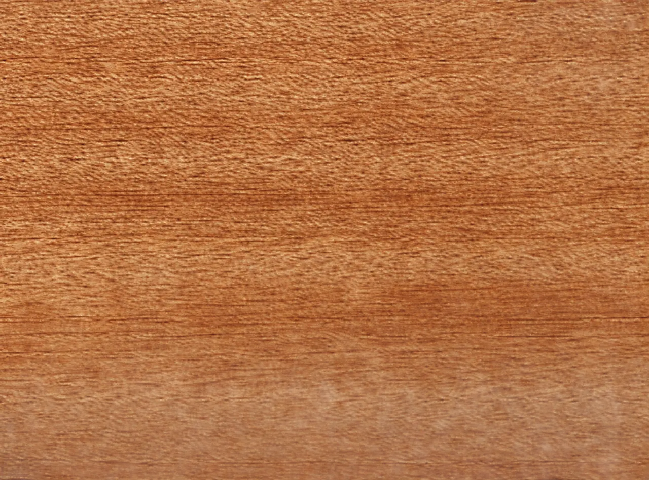 Gros plan sur une surface de bois brun-orangé au veinage fin et horizontal.